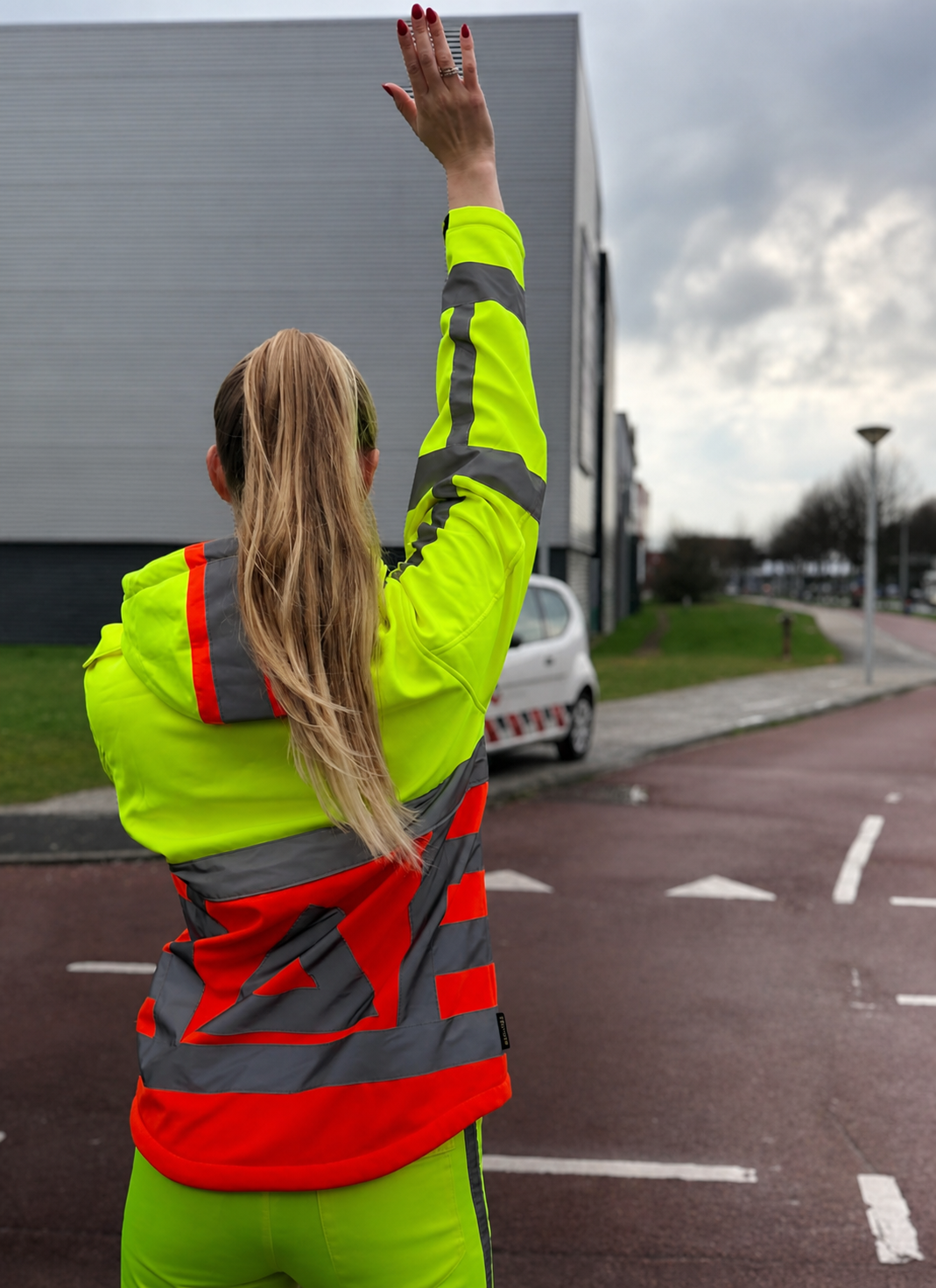 Verkeersbegeleider in hoge zichtbaarheidskleding begeleidt verkeer op locatie